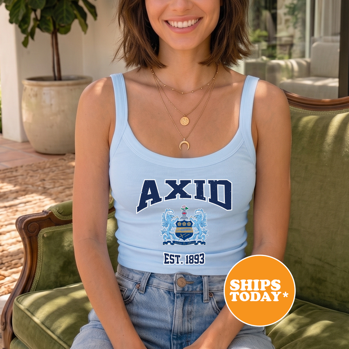 A woman wearing a light blue tank top with the word "AXID" printed on it, sitting on a green chair.