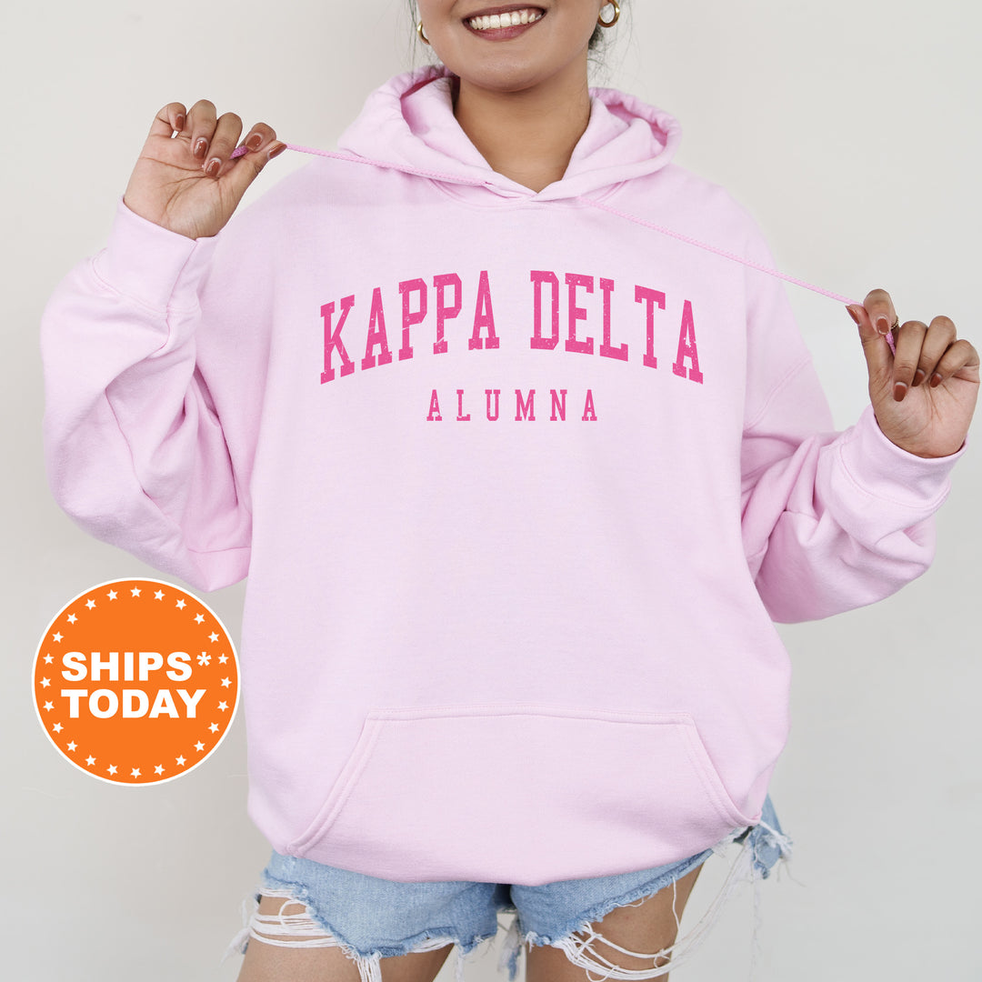 a woman wearing a pink kapa delta hoodie