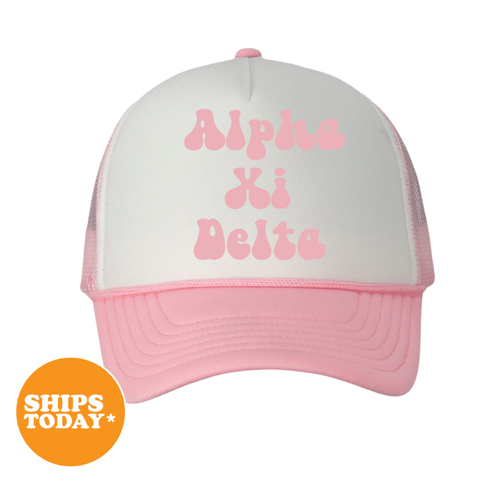 A pink and white baseball cap with the text "Alpha Kappa Delta" printed on it.