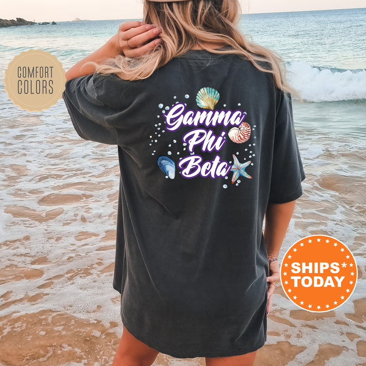 a woman standing on a beach wearing a black shirt