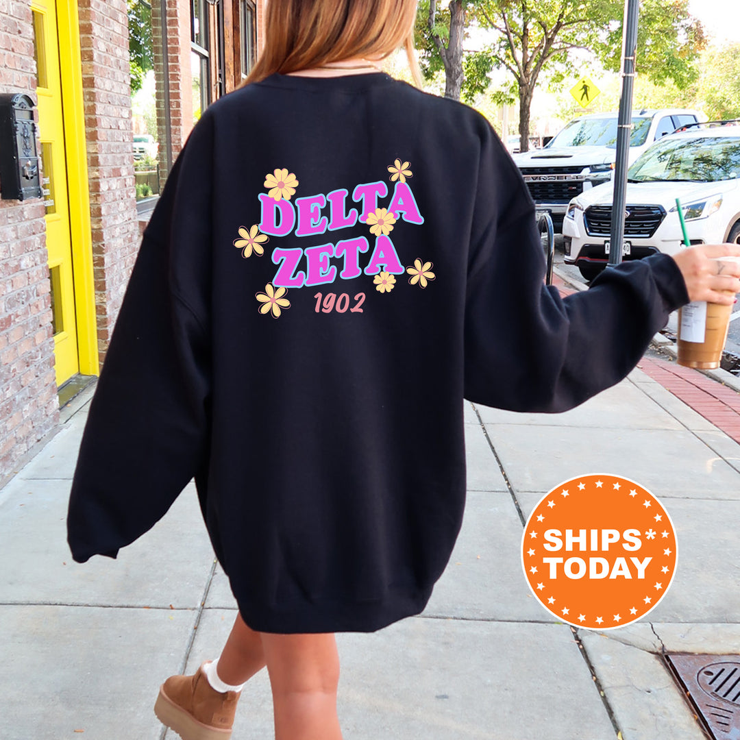 A person wearing a black sweatshirt with the Delta Zeta logo and the year 1902 printed on it, walking down a sidewalk.