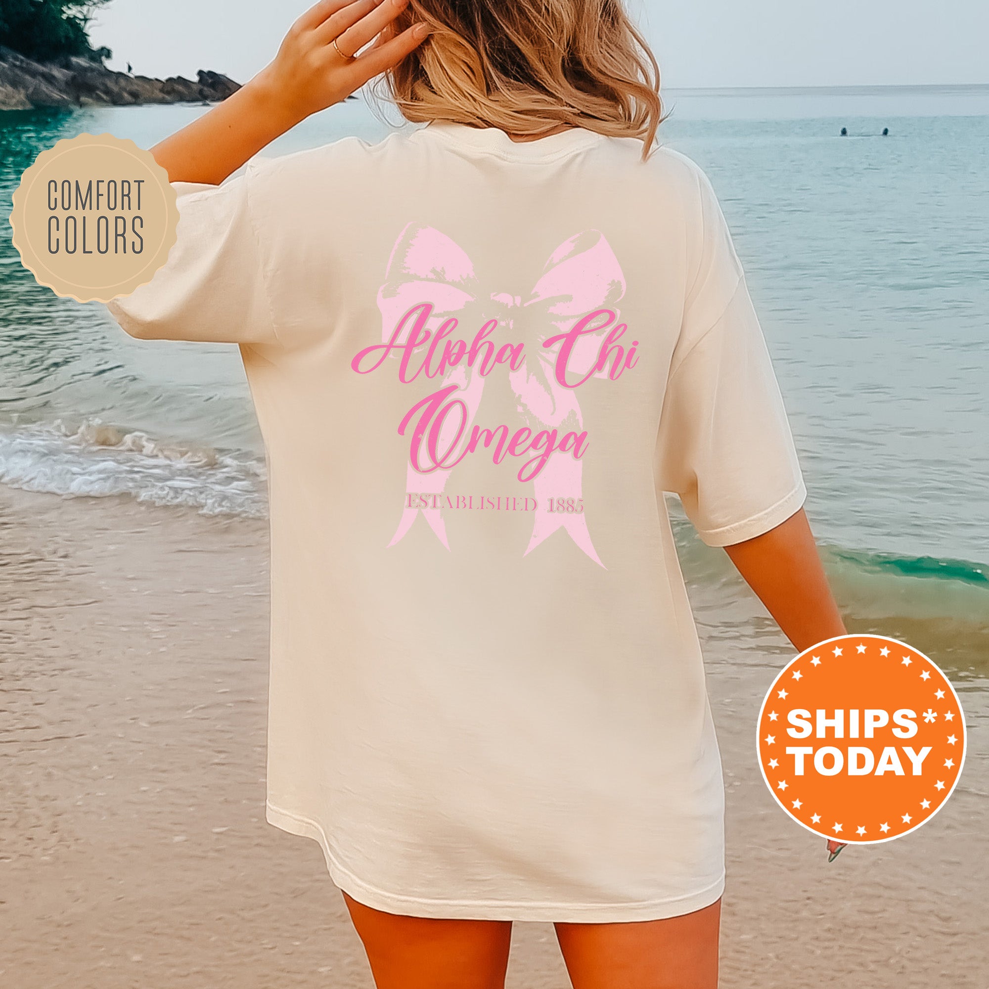 a woman standing on a beach wearing a shirt with a pink ribbon