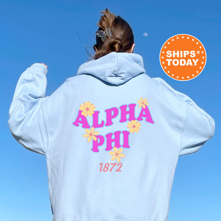 A person wearing a light blue hoodie with the text "ALPA Phi 1872" printed on it, standing against a clear blue sky.