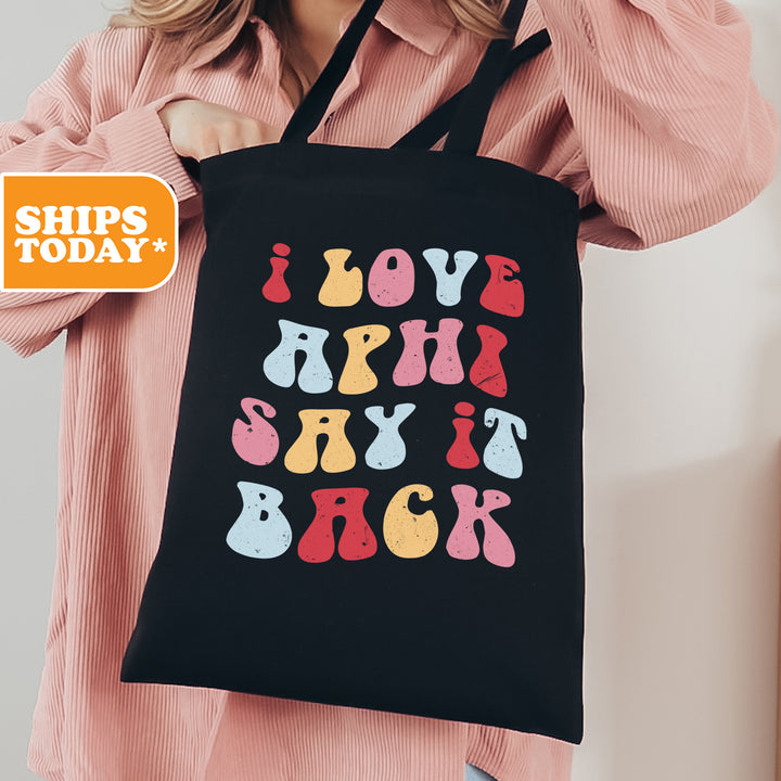a woman holding a black tote bag that says i love hippy shit back