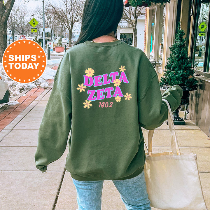 A person wearing a green sweatshirt with the Delta Zeta logo and the year 1902 printed on it, walking on a sidewalk.