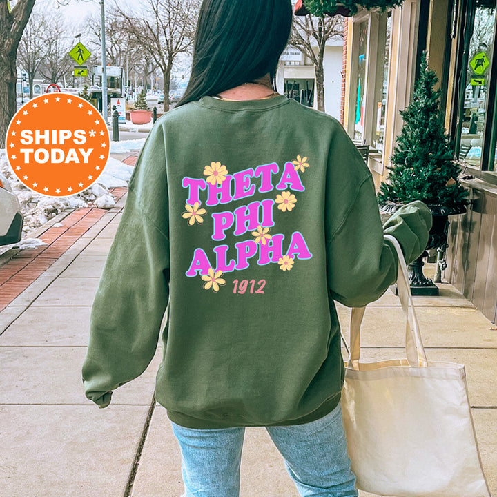 A woman wearing a green sweatshirt with the text "THETA PHI ALPHA 1912" printed on it, walking down a city street.