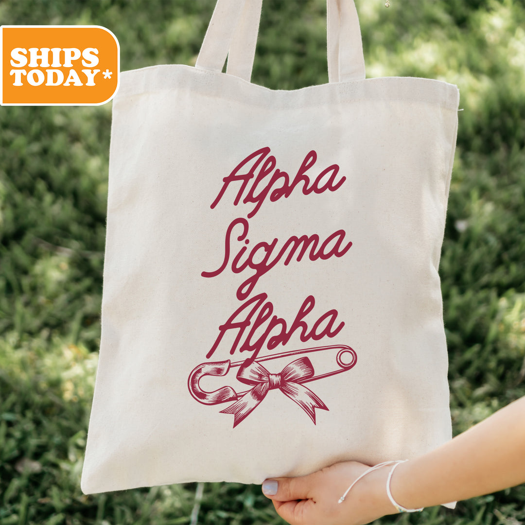 a person holding a tote bag with the words, alphabet, and scissors