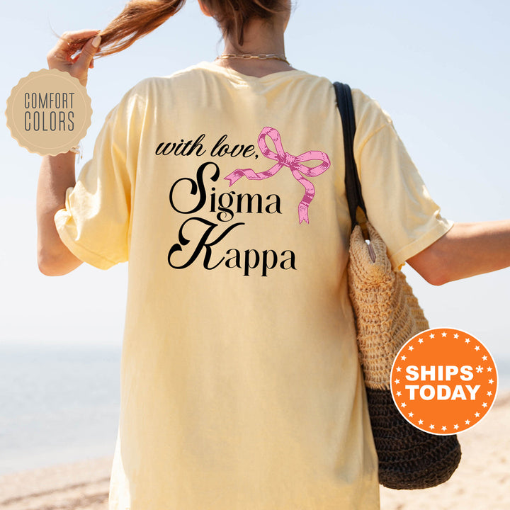 a woman walking on the beach with a pink ribbon on her shirt