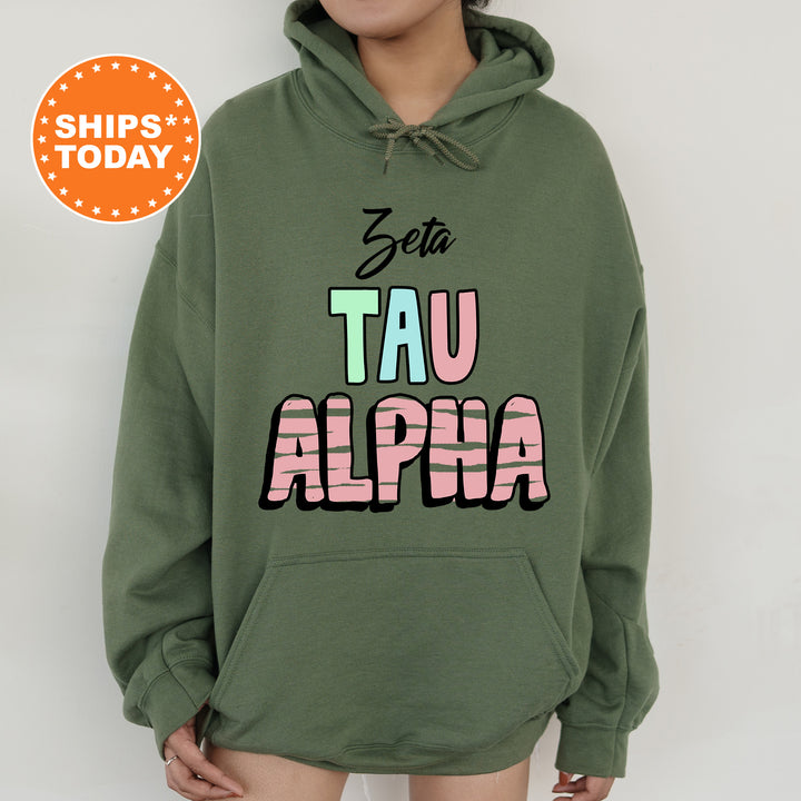 a woman wearing a green hoodie with the word tau alpha printed on it