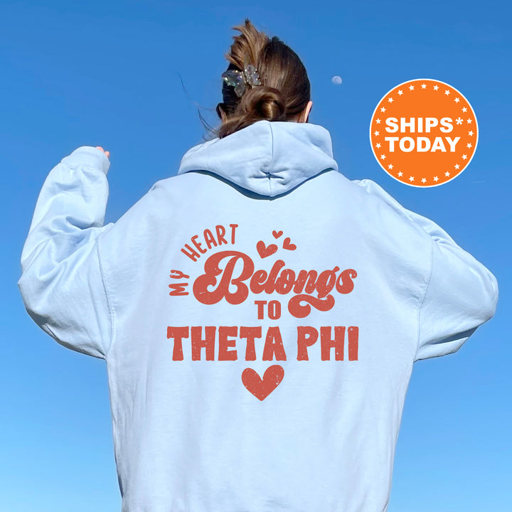 a woman wearing a white hoodie that says heart belongs to thea phi