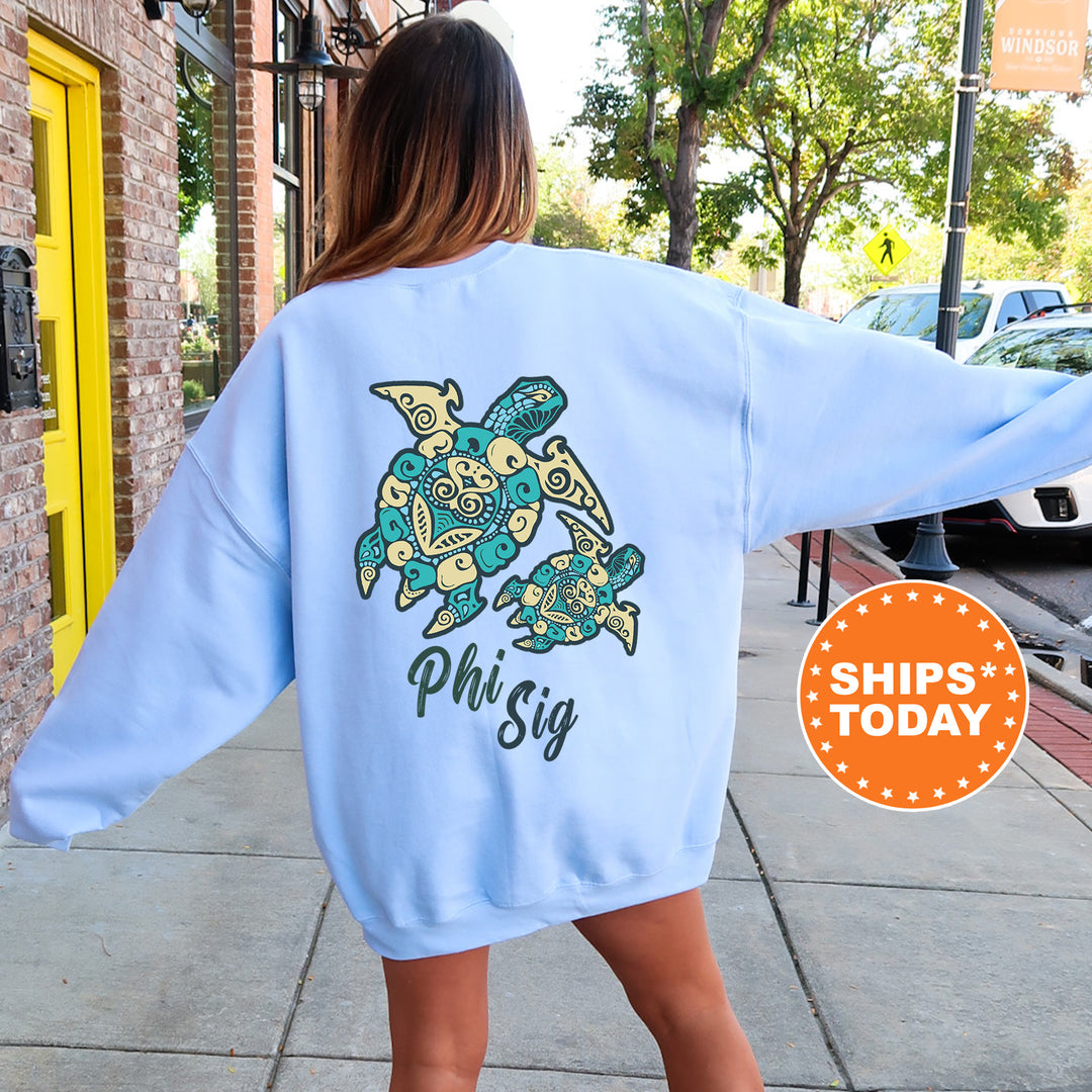 A woman wearing a light blue sweatshirt with a colorful turtle design on the back, standing on a sidewalk.