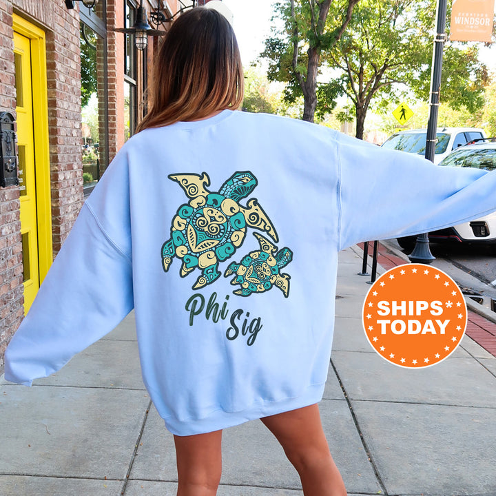 A woman wearing a light blue sweatshirt with a colorful turtle design on the back, standing on a sidewalk.