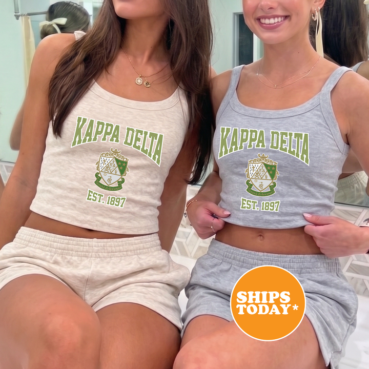 Two women wearing matching white and gray tops with the Kappa Delta logo, posing together in front of a mirror.