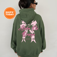 a woman wearing a green hoodie with a pink bow on it