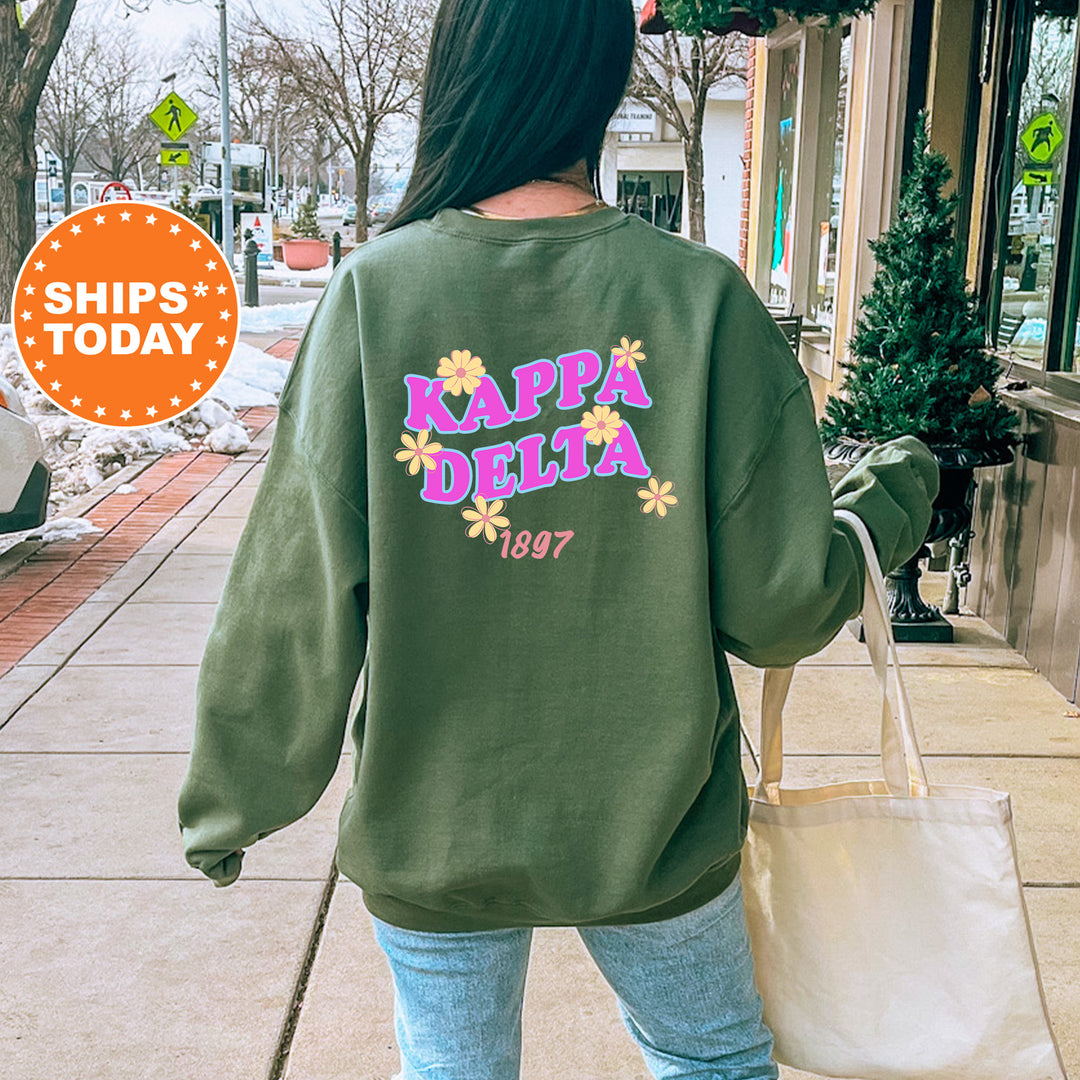 A person wearing a green sweatshirt with the text "KAPPADELTA 1997" printed on it, walking on a sidewalk.