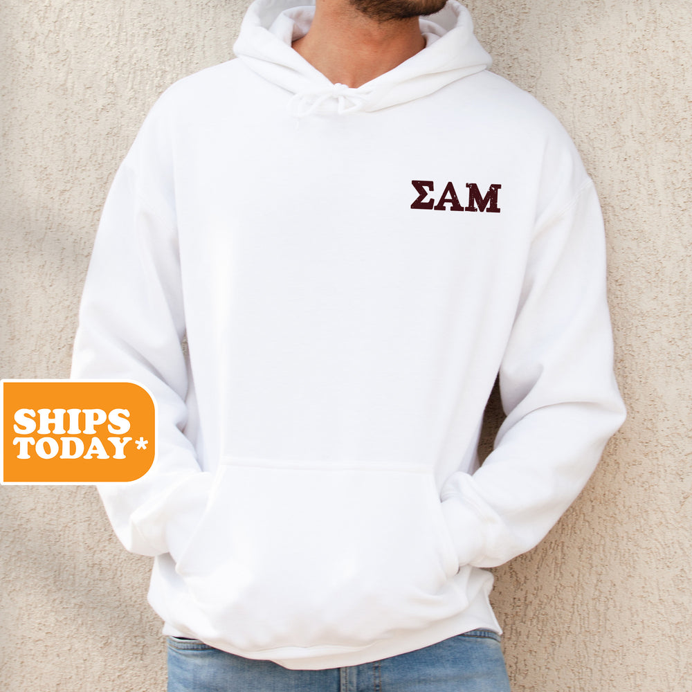 a man standing against a wall wearing a white hoodie