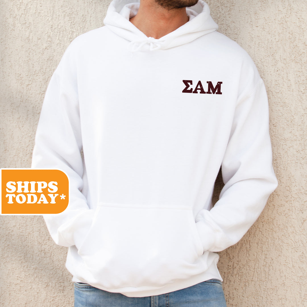 a man standing against a wall wearing a white hoodie