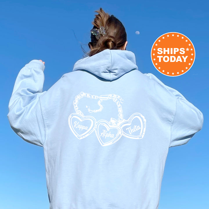 A person wearing a light blue hoodie with a graphic design on the back, including three heart-shaped symbols and text.