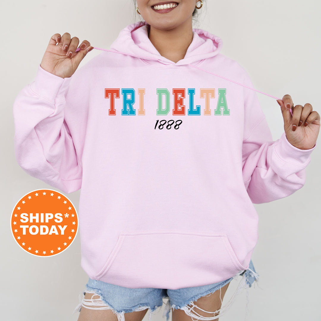 a woman wearing a pink hoodie with the word tri delta printed on it