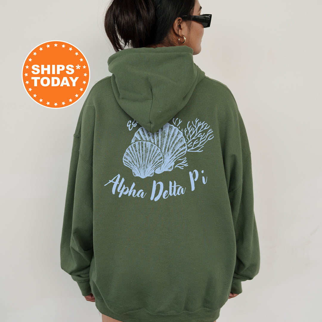 A person wearing a green hoodie with a graphic of seashells and the text "Alpha Delta Pi" printed on it.