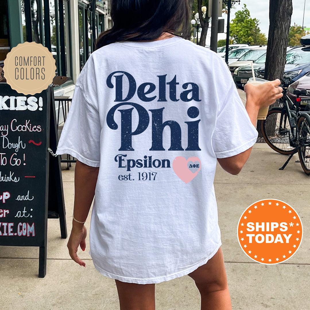 a woman walking down a sidewalk while wearing a delta phi shirt