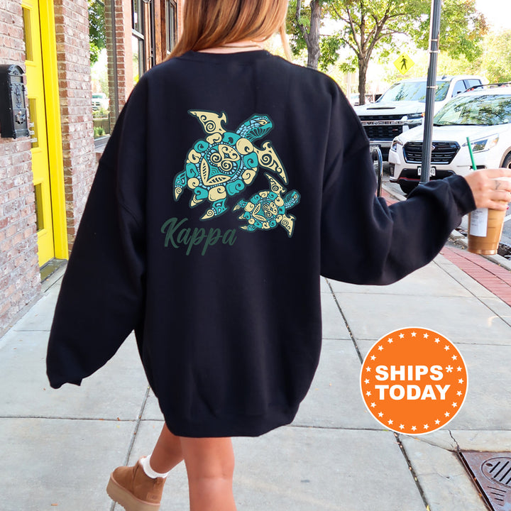 A person wearing a black sweatshirt with a colorful turtle design and the word "Kappa" printed on it, walking on a sidewalk.