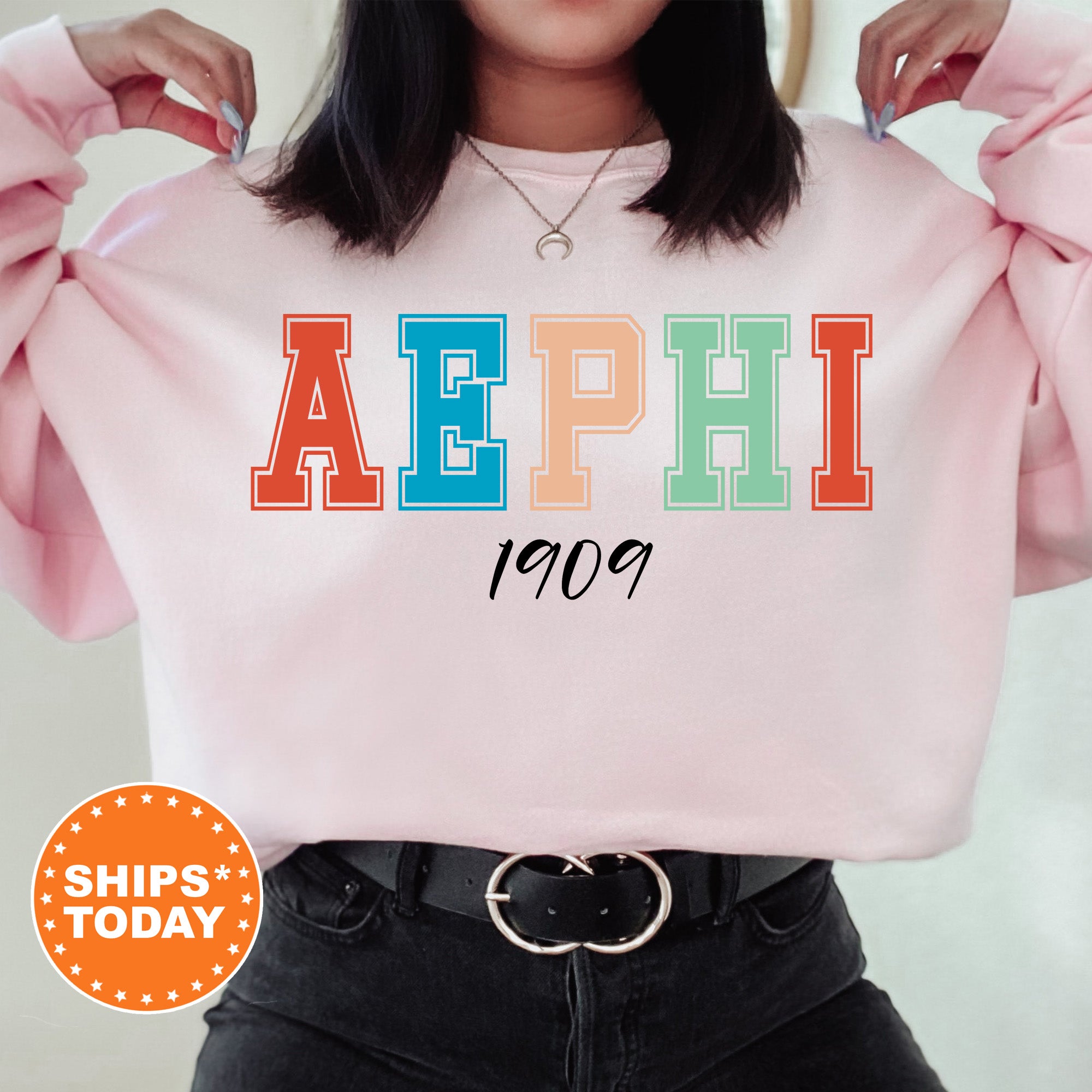 a woman wearing a pink sweatshirt with the word aephi printed on it