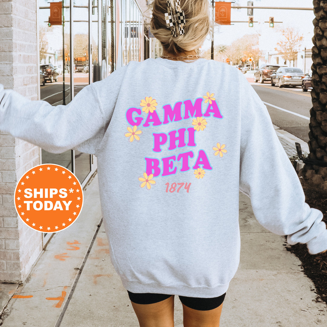 A person wearing a gray sweatshirt with the text "GAMMA PHI BETA" printed on it, standing on a sidewalk with a traffic light in the background.