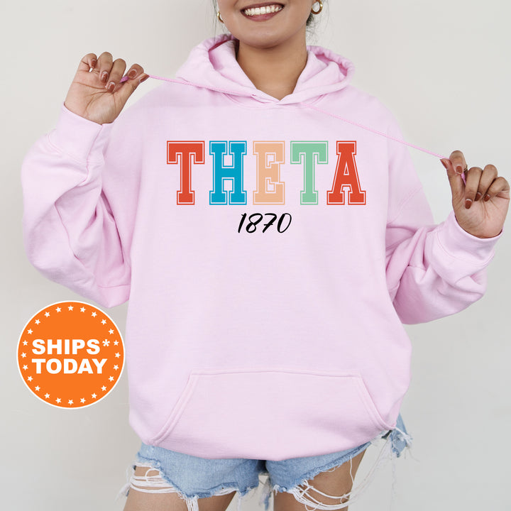 a woman wearing a pink hoodie with the word theta printed on it