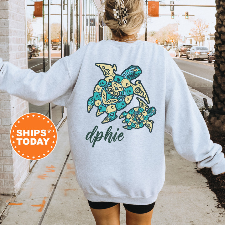 A person wearing a grey sweatshirt with a colorful turtle design on the back, standing on a sidewalk with a traffic light in the background.