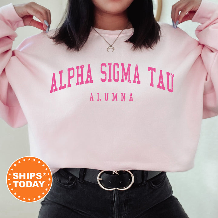 a woman wearing a pink sweatshirt with the words alpha sioma tau on it