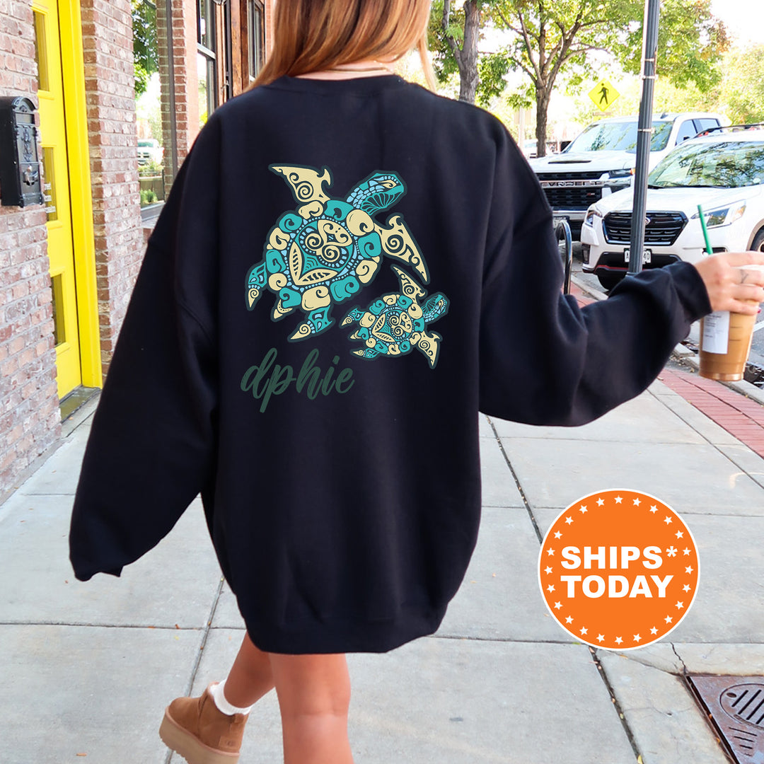 A person wearing a black sweatshirt with a colorful turtle design and the name "dphie" printed on it, walking on a sidewalk.