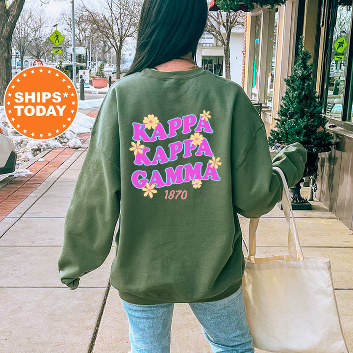 A person wearing a green sweatshirt with the text "KAPPAN Kappa Kappa Kappa" printed on it, walking on a sidewalk.