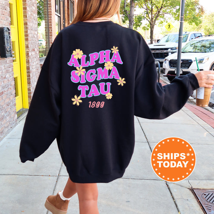 A person wearing a black sweatshirt with the text "ALPHA SIGMA TAU 1899" printed on it, walking down a sidewalk.