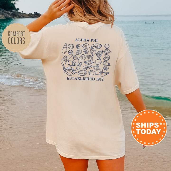 a woman standing on a beach wearing a white shirt