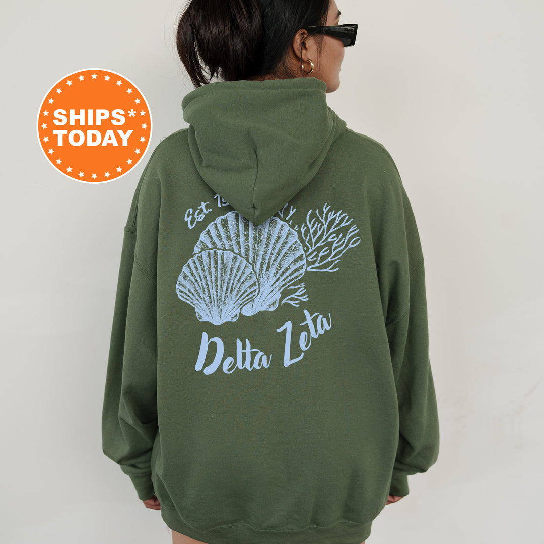 A person wearing a green hoodie with a graphic design of seashells and the text "Delta Zeta" printed on the back.