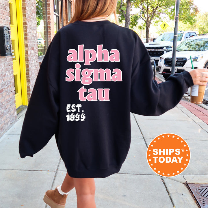 A person wearing a black sweatshirt with pink text and a logo, walking on a sidewalk.