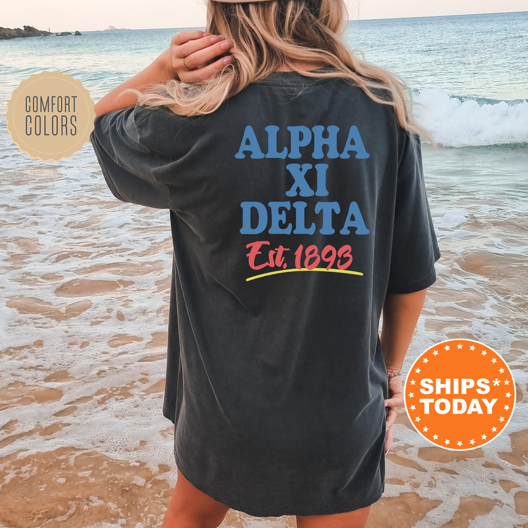 A woman wearing a black t-shirt with text printed on it, standing on a beach with waves in the background.