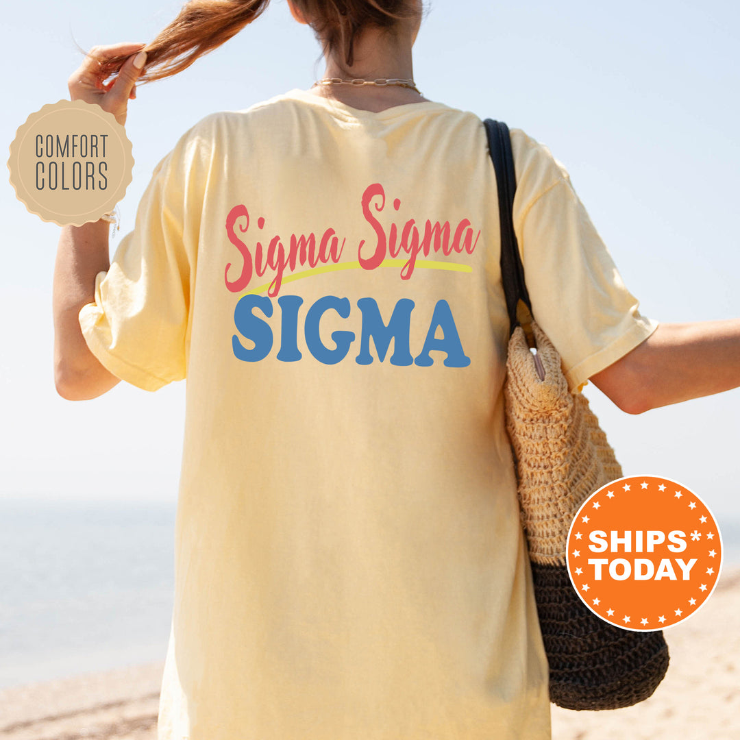 A person wearing a yellow t-shirt with the text " Sigma Sigma" printed on it, standing on a beach with a handbag.