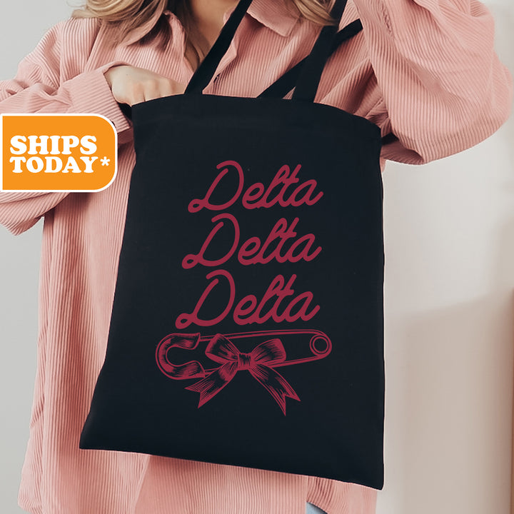 a woman holding a black tote bag with the words delta delta on it