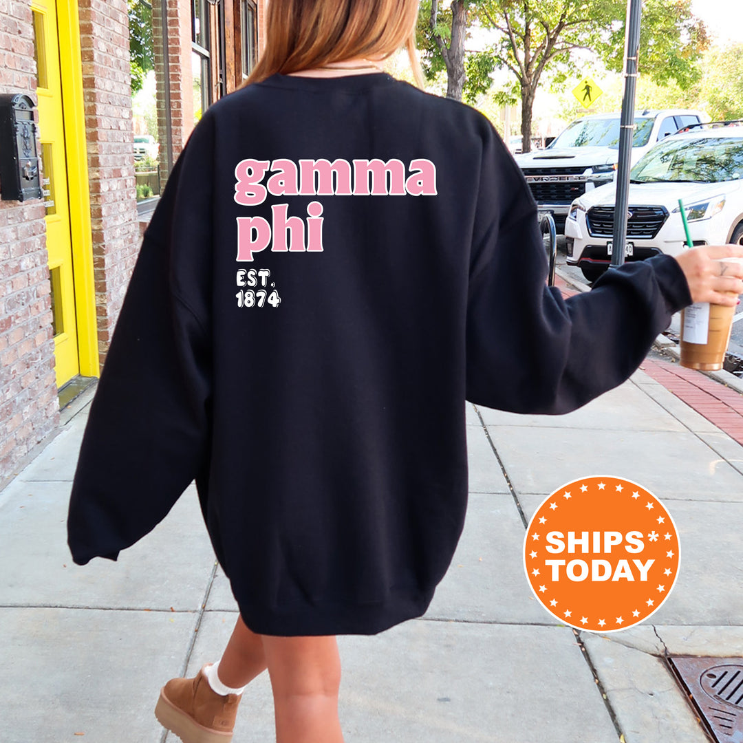 A person wearing a black sweatshirt with the text "gamma phi" printed on it, walking down a sidewalk.