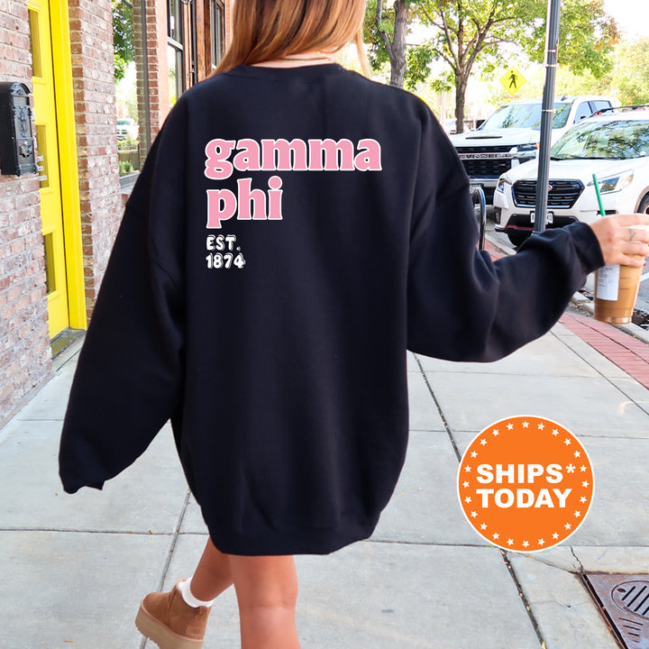 A person wearing a black sweatshirt with the text "gamma phi" printed on it, walking down a sidewalk.