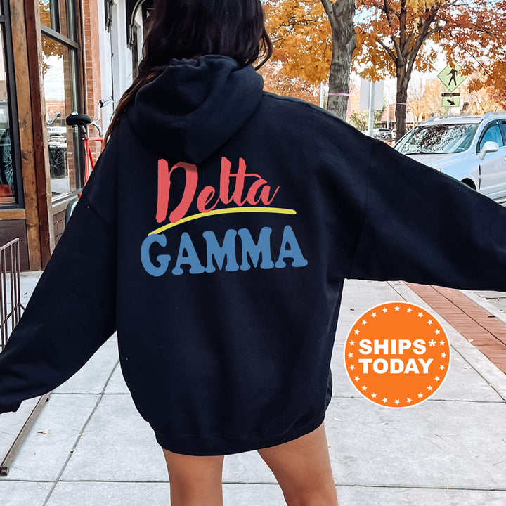 A person wearing a black hoodie with the Delta Gamma sorority logo on the back is standing on a sidewalk.