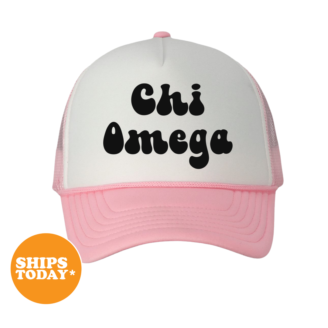 A pink and white baseball cap with the text "Chi Omega" printed on it.
