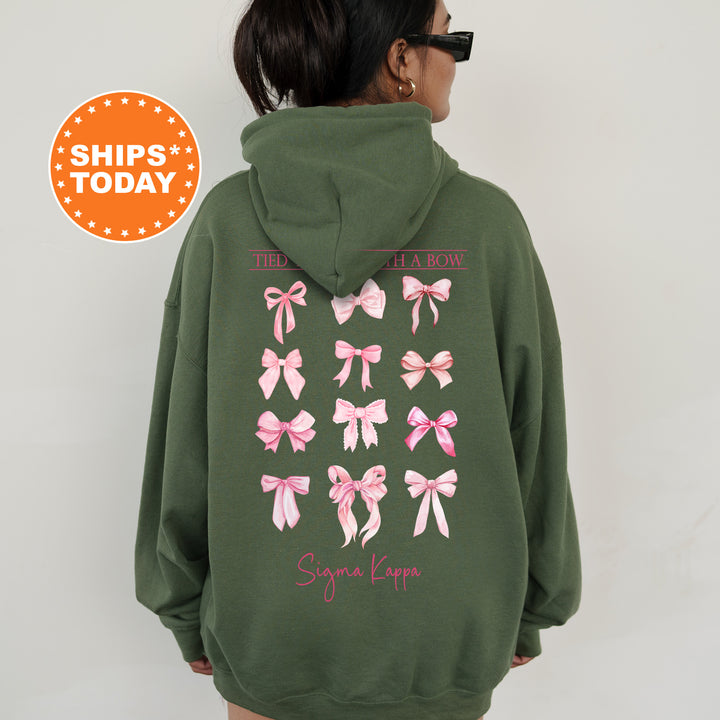 A person wearing a green hoodie with pink bows printed on the back.