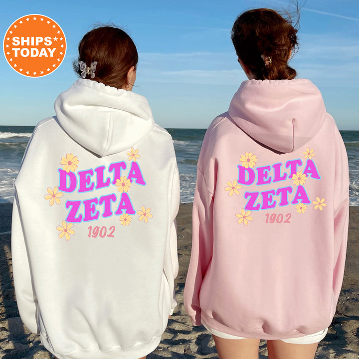 Two women wearing hooded sweatshirts with the Delta Zeta logo standing on a beach.