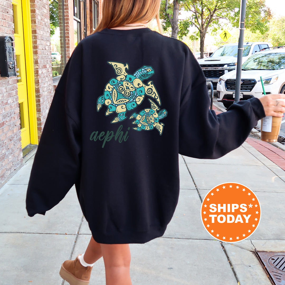 A person wearing a black sweatshirt with a colorful turtle design on the back is walking down a sidewalk.