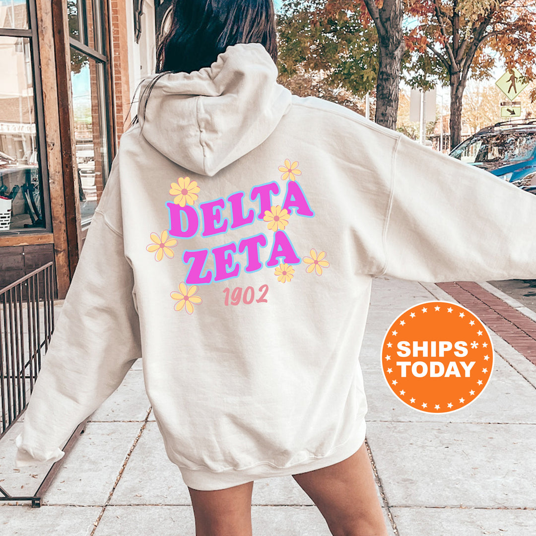 A person wearing a white hoodie with the Delta Zeta logo and the year 1902 printed on it, standing on a sidewalk.