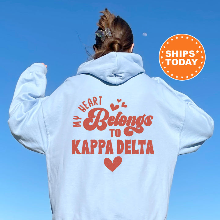 a woman wearing a white hoodie that says heart belongs to kapp delta