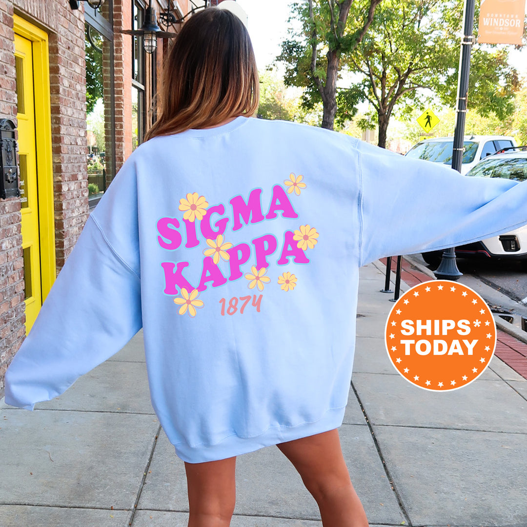 A woman wearing a light blue sweatshirt with the text "SIGMA KAPPAS 1874" printed on it, standing on a sidewalk.